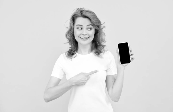 excited young woman isolated overyellow background using mobile phone showing ok gesture. - Photo, Image