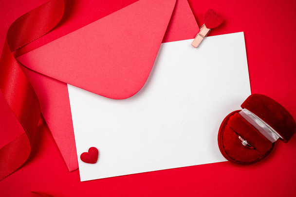 Tarjeta de felicitación Valentine. Corazón rojo, regalo romántico sobre fondo rojo amor. Decoración del día de San Valentín para la tarjeta laica plana con espacio de copia - Foto, Imagen
