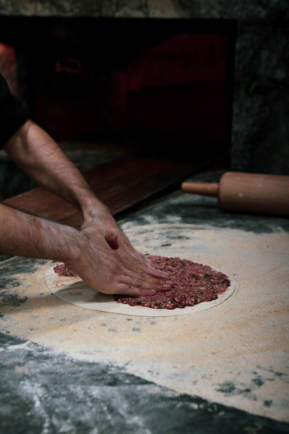 Faire une pizza turque ou lahmacun - restauration rapide et street food populaire dans les pays méditerranéens. Pâte, viande hachée et ingrédients végétaux pour la cuisson du pide turc. - Photo, image