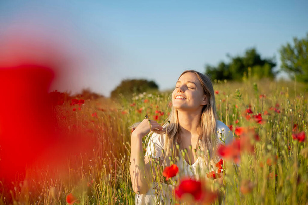 jolie jeune femme profiter du soleil dans le champ de pavot - Photo, image