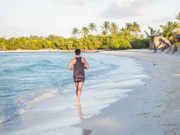 Genç adam Atlantik Okyanusu kıyısında koşuyor. - Fotoğraf, Görsel