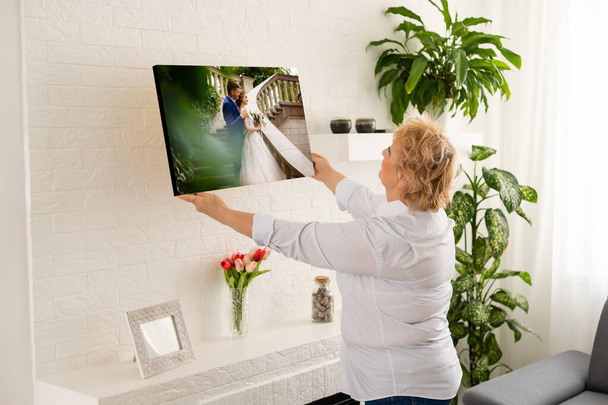 Женщина, держащая свадебную фотографию, распечатывает холст с галереей. - Фото, изображение
