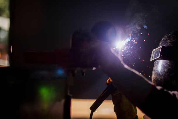Чоловік працює на металевій зварювальній сталі, використовуючи електрозварювальний апарат для зварювання
. - Фото, зображення