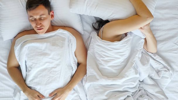 Kobieta próbuje zasnąć i budzi się chrapiący mąż w łóżku - Zdjęcie, obraz