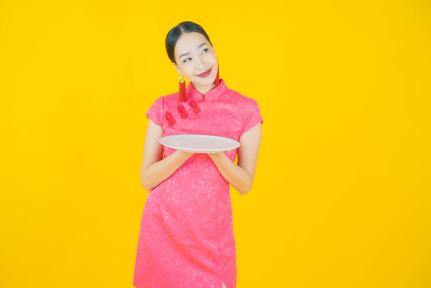 Portrait beautiful young asian woman smile with empty plate dish on color background - Photo, Image