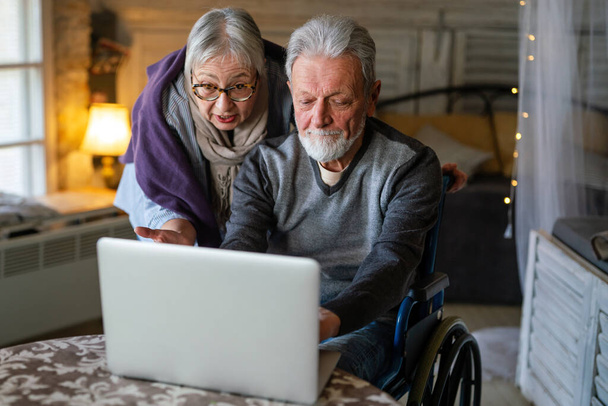 Feliz pareja de ancianos utilizando el ordenador portátil en casa y divertirse juntos. Concepto gente tecnología - Foto, imagen