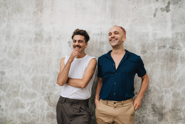 Gay Couple standing at a wall outdoors. Two men in face mask at grey wall - Zdjęcie, obraz