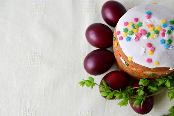 Traditional Easter cake with decorative glaze. Orthodox food after fasting on the Easter holiday. Red-painted chicken eggs on a light tablecloth - Photo, image