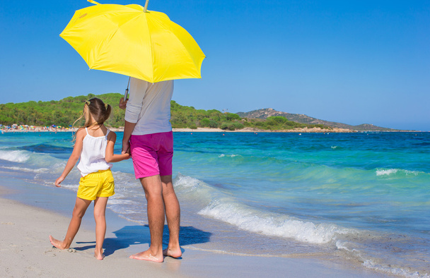 οπίσθια όψη του πατέρα και κόρη στην Λευκή παραλία με κίτρινο ομπρέλα - Φωτογραφία, εικόνα