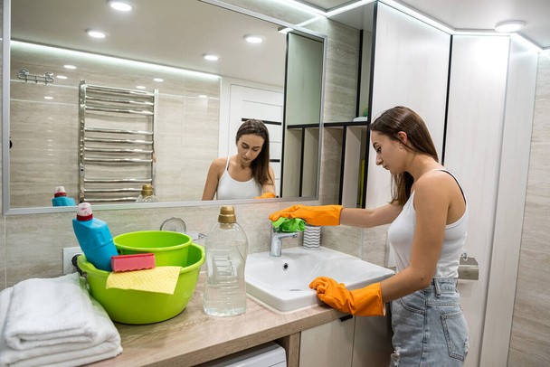Nuori nainen siivoamassa. Siivouspalvelut kylpyhuoneessa - Valokuva, kuva