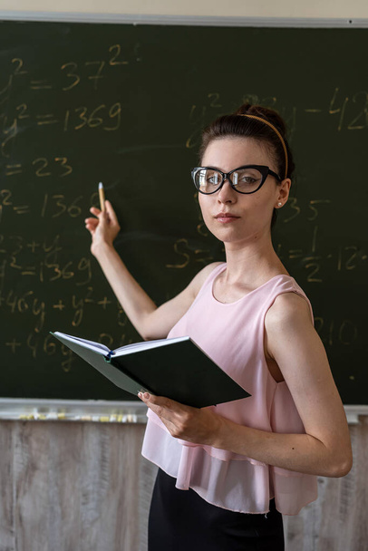Έξυπνη μαθήτρια που γράφει σε πίνακα που ολοκληρώνει μαθηματικούς τύπους άλγεβρας, εκπαιδευτική έννοια  - Φωτογραφία, εικόνα