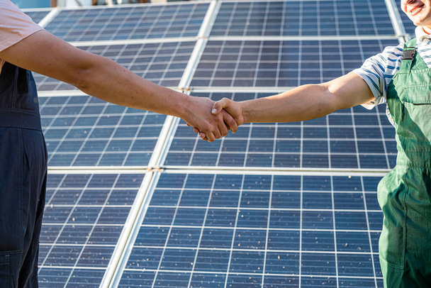 Мужские рукопожатия вблизи солнечных батарей . - Фото, изображение