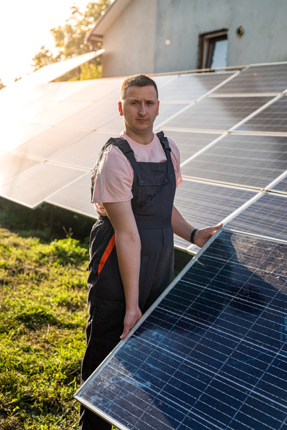 young caucasian man in uniform works at a solar station. Concept of green energy - Photo, Image
