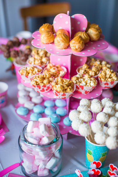 Marshmallow, sweet colored meringues, popcorn, custard cakes and white cake pops on festive table - Photo, Image