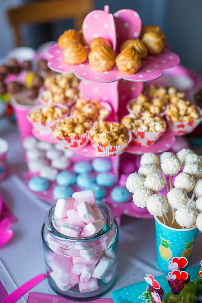 Marshmallow, zoete gekleurde schuimgebakjes, popcorn, vla taarten en witte cake springt op tafel - Foto, afbeelding