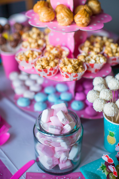 Ibišek, barevné sladké pusinky, popcorn, pudinkové koláčky a bílý dort pops na slavnostní stůl - Fotografie, Obrázek