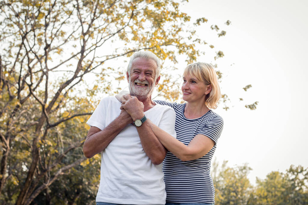 Idősebb pár a parkban. Boldog mosolyt a nyugdíjas párnak egy parkban egy nyaraláson. Romantikus érett pár ősszel a parkban. - Fotó, kép