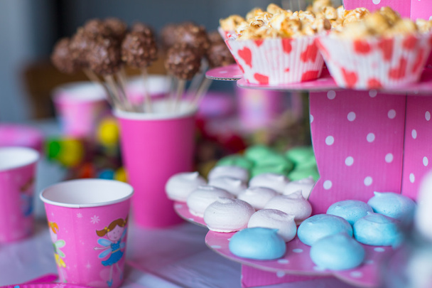 barevné sladké pusinky, popcorn, pudinkové zákusky a koláče se objeví na stole - Fotografie, Obrázek