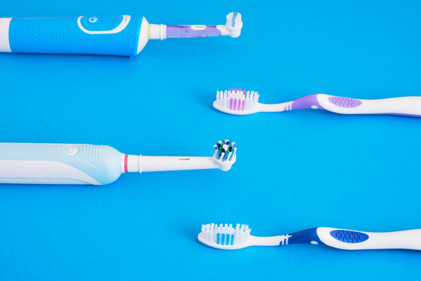 different toothbrushes on blue background, electric toothbrush or plastic toothbrushes, eco-friendliness lifestyle concept, efficiency of brushing teeth - Foto, Imagen