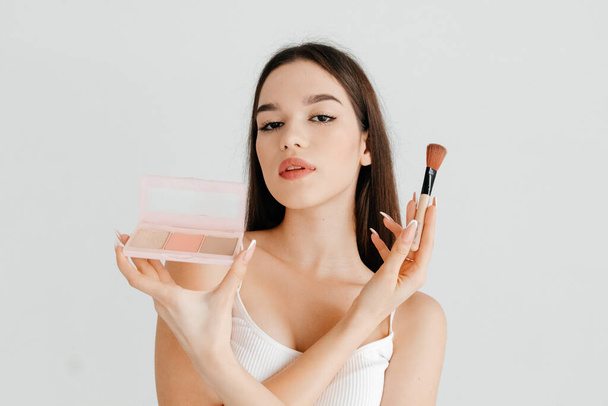 Close up photo of attractive girl holding a contouring palette, wants to make perfect make-up for prom night over white color background - Photo, Image