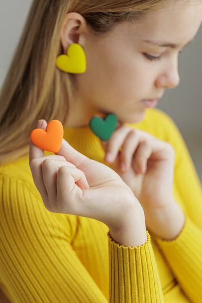 Teenage girl chooses jewelry earrings. Heart shaped earrings. St. Valentines Day. - Fotografie, Obrázek