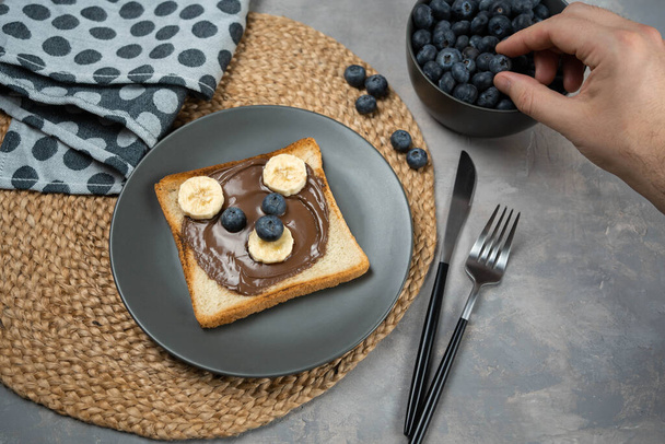 Colazione o pranzo per bambini o brindisi con crema di nocciole al cioccolato, banana e mirtillo a forma di simpatico orso. - Foto, immagini