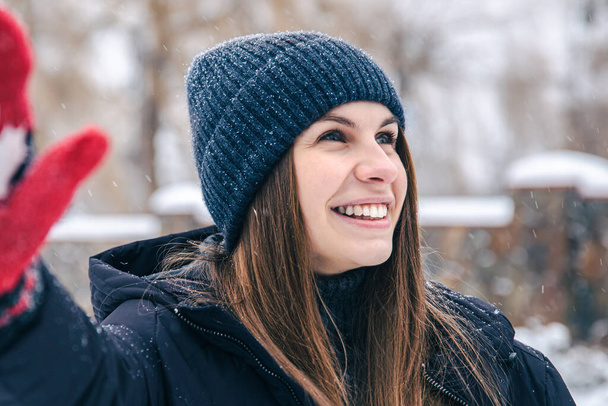 Счастливая молодая женщина в красных рукавицах с флагом Канады в снежную погоду. - Фото, изображение