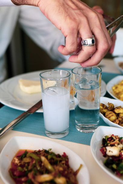 Mesa de jantar tradicional turca e grega com bebida alcoólica especial Raki. Ouzo e Turkish Raki é um anis seco aperitivo aromatizado que é amplamente consumido na Turquia, Grécia, Chipre e Líbano
 - Foto, Imagem