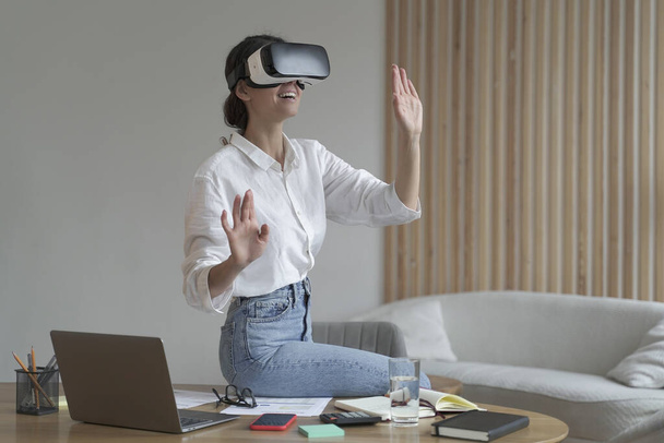 Empresaria en ropa formal elegante sentada en la oficina y usando tecnologías VR en el trabajo - Foto, imagen