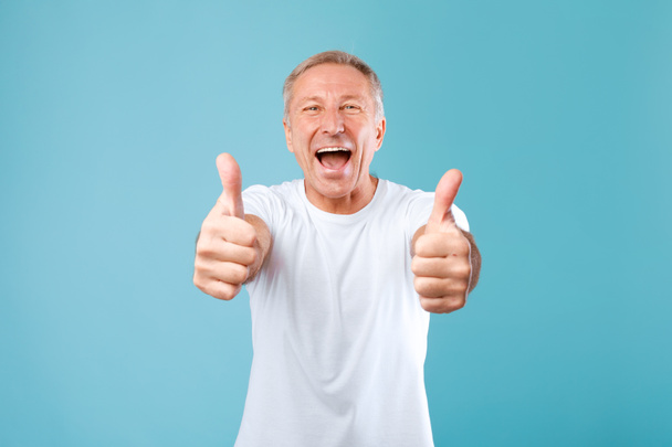 Excited mature man gesturing thumbs up and smiling - Photo, image