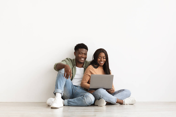 Feliz hombre negro y mujer usando cuaderno juntos - Foto, imagen