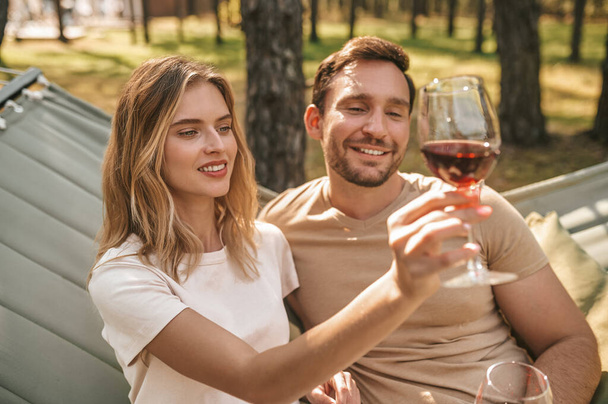 Young smiling couple holding glasses with wine and looking happy - Фото, зображення