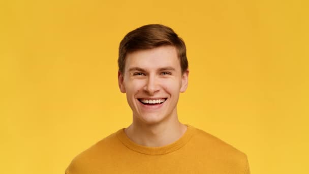 Man Smiling Raising Eyebrows Looking At Camera Over Yellow Background - Filmati, video