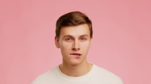 Playful Millennial Guy Biting Lips Posing Over Pink Background - Filmagem, Vídeo