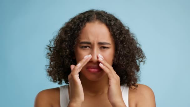 Enfermo negro dama tocando dolor de nariz sobre fondo azul - Metraje, vídeo