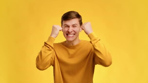 Millennial Man Shaking Fists Γιορτάζοντας την επιτυχία Ποζάροντας πάνω από κίτρινο φόντο - Πλάνα, βίντεο