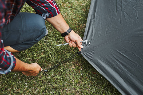 Man putting up a tent at camping during summer vacation. Preparing campsite to rest and relax. Spending vacations outdoors close to nature - Foto, Imagem
