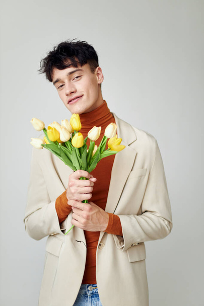 Photo young boyfriend in white jacket with a bouquet of yellow flowers elegant style Lifestyle unaltered - Φωτογραφία, εικόνα