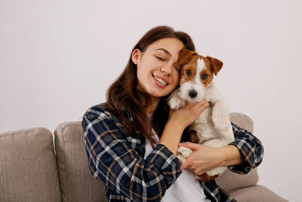 Portrait of young beautiful woman playing with her adorable four months old wire haired Jack Russel terrier puppy. Loving girl with rough coated pup having fun. Background, close up, copy space. - Valokuva, kuva