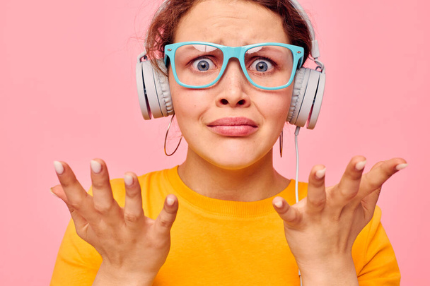 cheerful woman wearing blue glasses listening to music on headphones isolated backgrounds unaltered - Photo, image