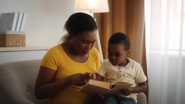 Παιδική Ανάπτυξη. Φροντίδα μαύρη μητέρα διδασκαλία λίγο γιο ανάγνωση στο σπίτι - Πλάνα, βίντεο