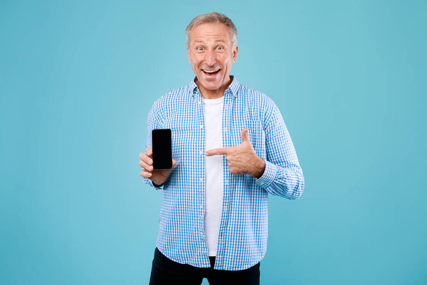 Izgatott érett férfi ujjal mutogat az üres okostelefon képernyőn - Fotó, kép