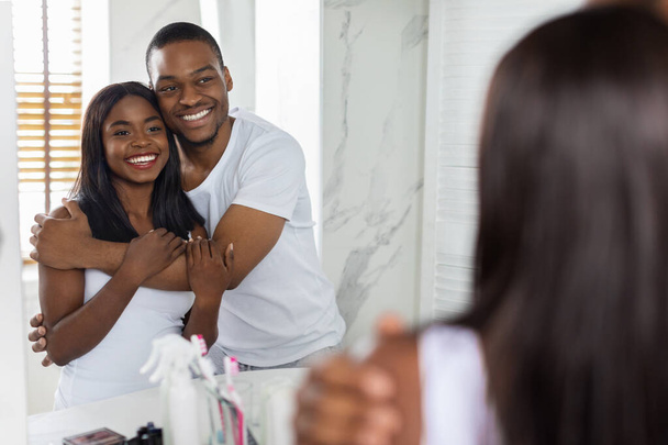 Pár domácích životů. Romantický černošky manželé objímající v blízkosti zrcadla v koupelně - Fotografie, Obrázek