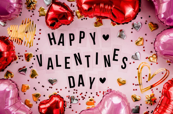 Stylish text frame with the inscription happy valentines day. Pink, red and gold hearts all around. Foil balloons top view of Valentine's Day. Copyspace. - 写真・画像