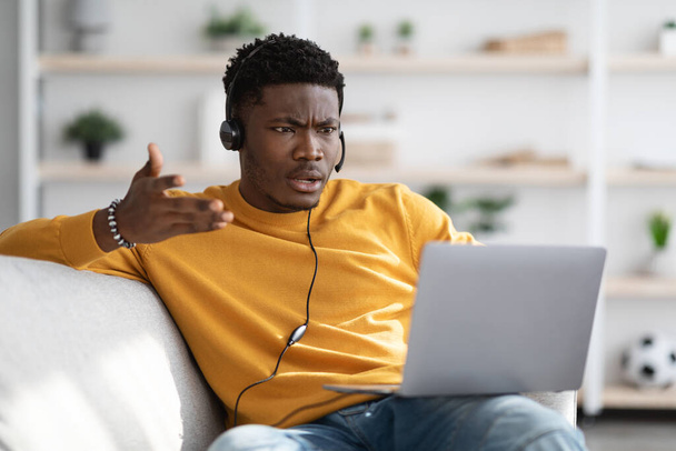 Furious black guy having video call, using laptop at home - Foto, imagen