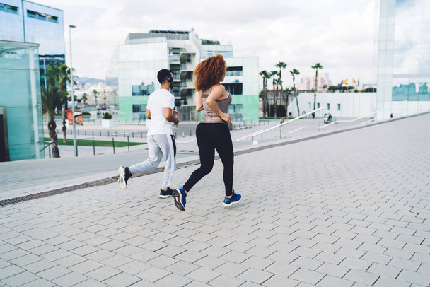 Back view of multiracial male and female friends training together on urban settings i morning having healthy lifestyle,young hipster guys running for reaching fitness goals and slimming in town - Φωτογραφία, εικόνα
