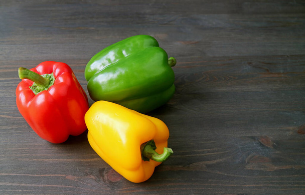 Vibrant Tricolor Bell Peppers Lined Up on Back Wooden Background - Foto, immagini