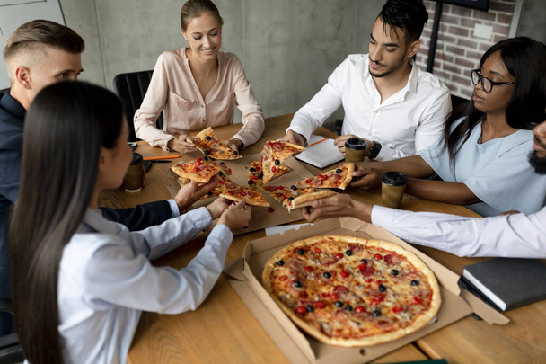 Skupina multietnických kolegů těší přestávka na oběd v kanceláři, jíst pizzu společně - Fotografie, Obrázek