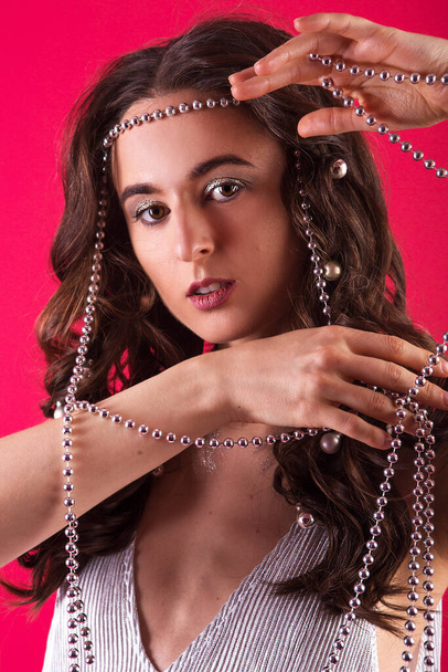 Retrato de una hermosa mujer con un collar de perlas de plata aislado sobre un fondo rojo. - Foto, Imagen