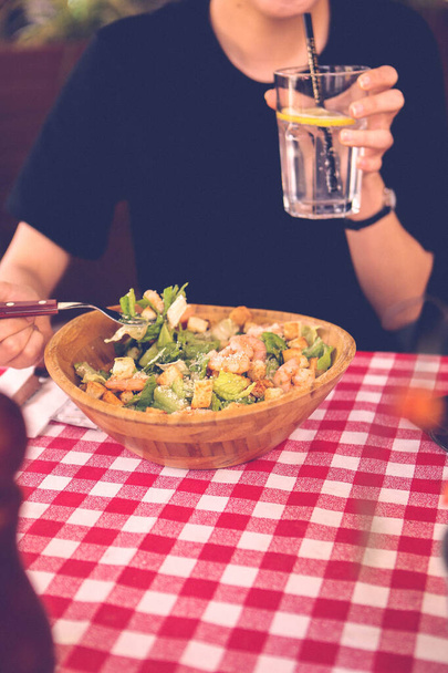 muotokuva houkutteleva valkoihoinen hymyilevä nainen syö salaattia, keskittyä käsin ja haarukka
. - Valokuva, kuva